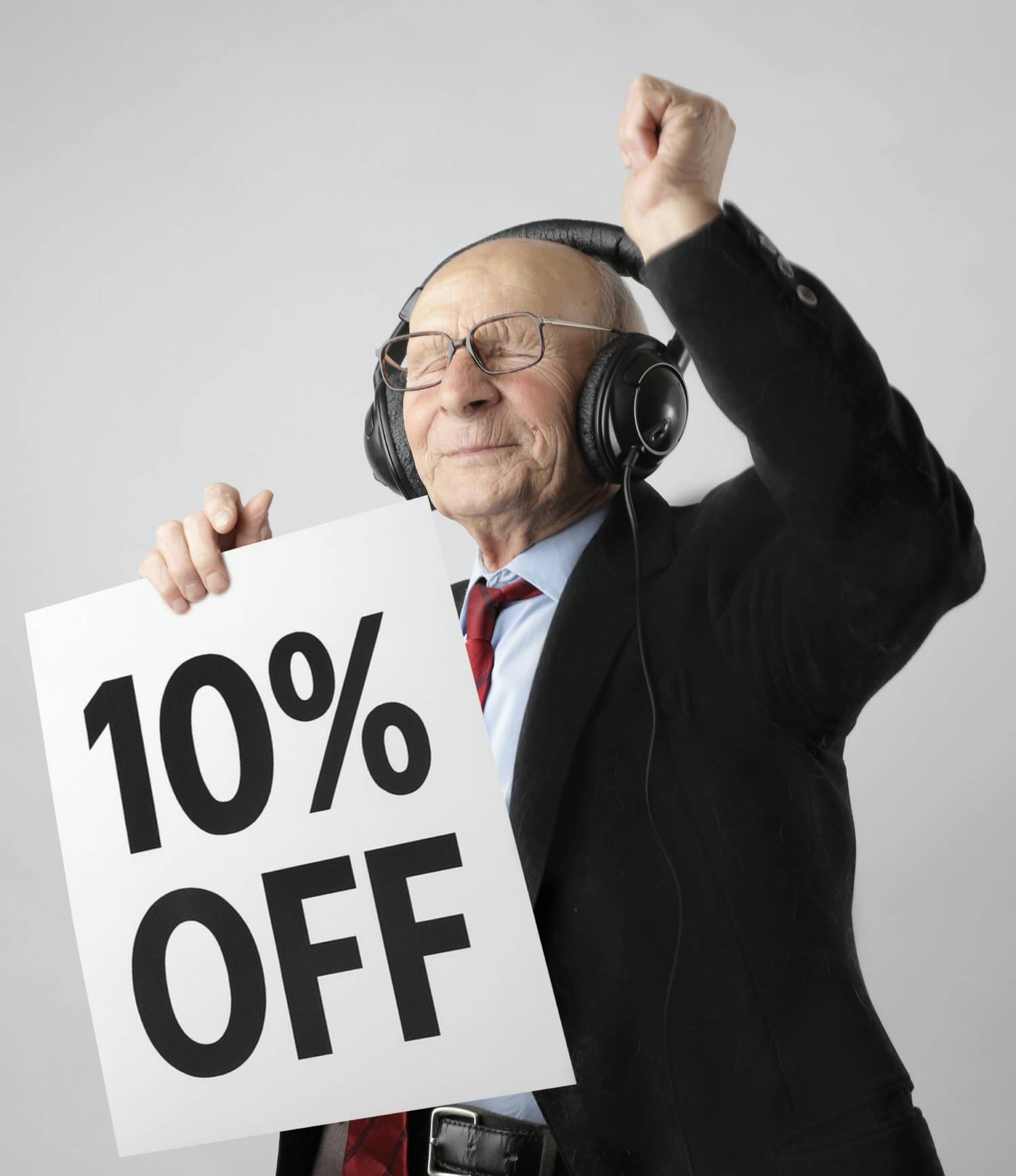 Man in suit with headphones holding a sign with '10% OFF' on a plain background