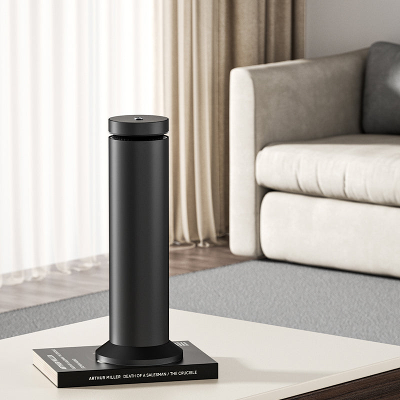 Black humidifier emitting steam on a marble desk with a computer monitor in the background.