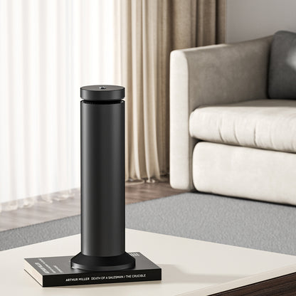 Black humidifier emitting steam on a marble desk with a computer monitor in the background.