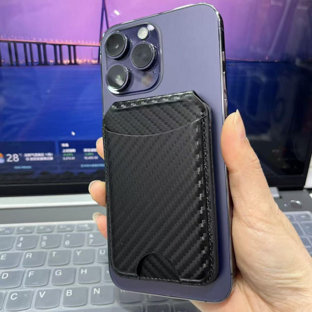 Hand holding a purple phone with a black iPhone Magnetic Wallet in front of a laptop screen.