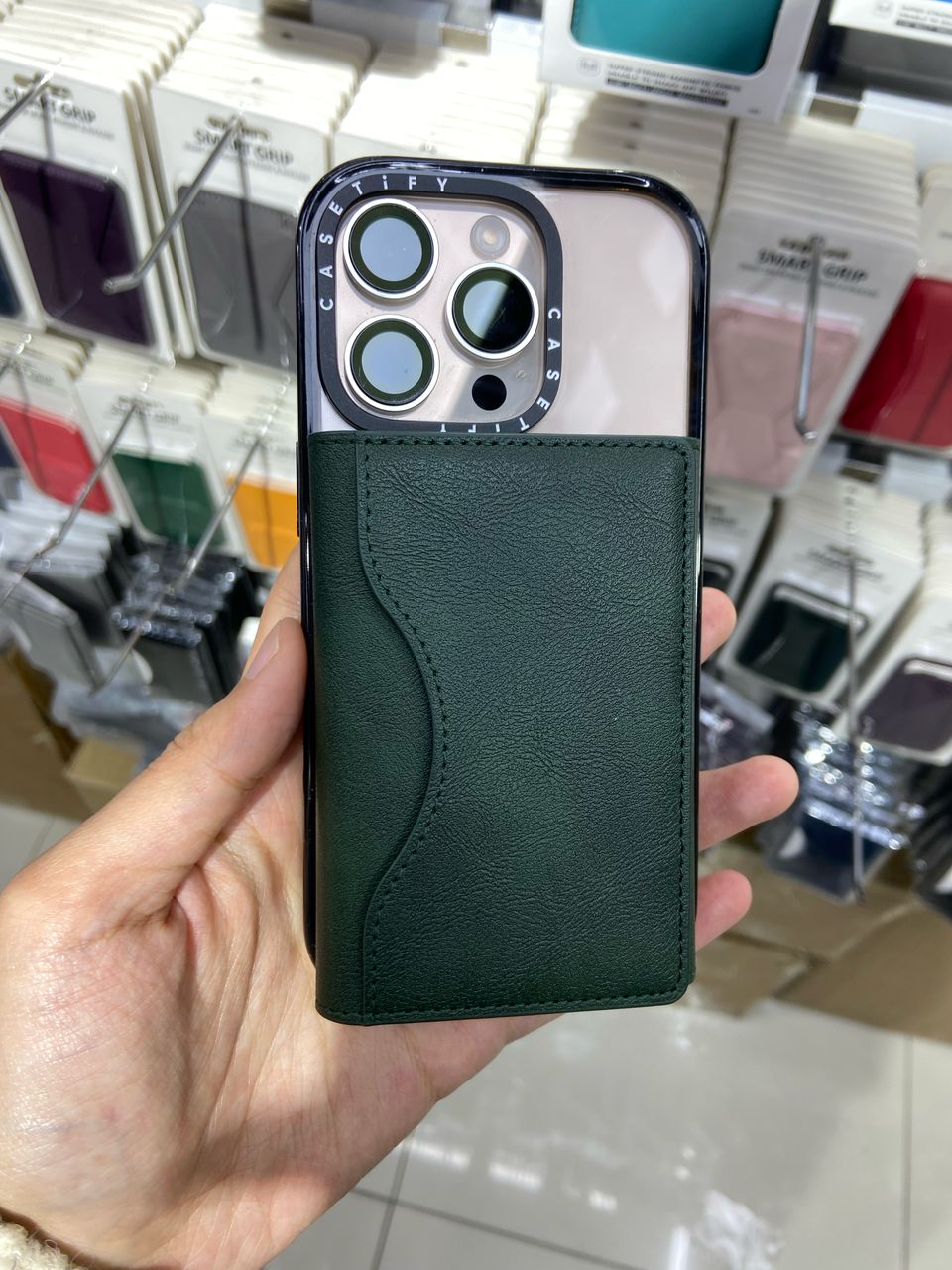 GreenHand Leather Magnetic iPhone Wallet  held in a hand with a blurred store background